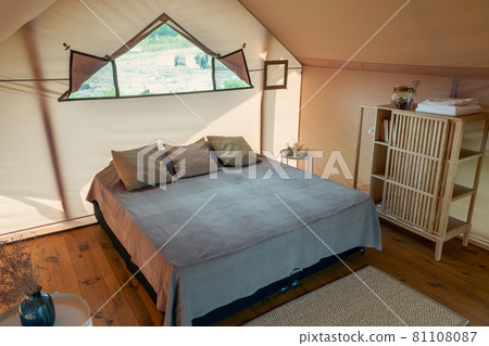 Large double bed with cushions standing on wooden floor of bedroom Large double bed with cushions standing on wooden floor of bedroom 81108087