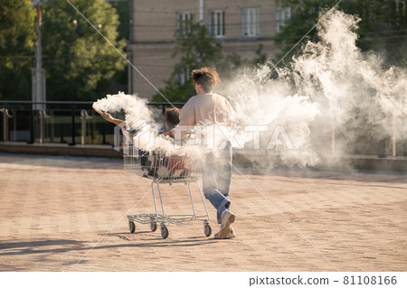Teenage dates having fun with firecrackers while guy pushing shopping cart with his girlfriend 81108166