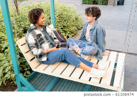 Teenage romantic couple in casualwear chatting outdoors Teenage romantic couple in casualwear chatting outdoors 81108474