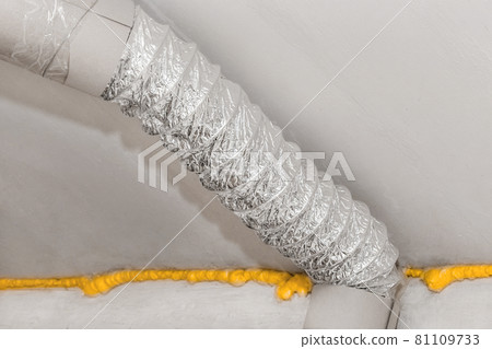 Ventilation air metal pipe under ceiling with construction polyurethane foam insulation at an industrial plant or factory 81109733