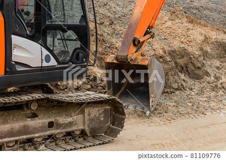 Crawler industrial machine excavator with a bucket on the background of a pile of sand at a construction site Crawler industrial machine excavator with a bucket on the background of a pile of sand at a construction site 81109776
