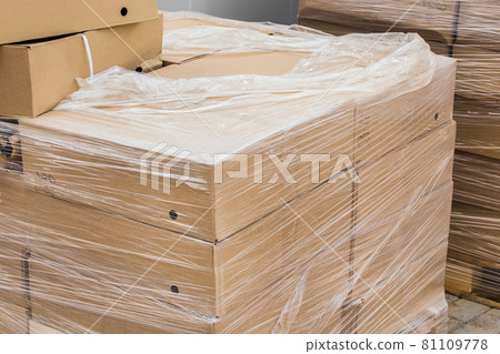 A bunch of cardboard boxes with building materials packed in plastic wrap at construction site A bunch of cardboard boxes with building materials packed in plastic wrap at construction site 81109778