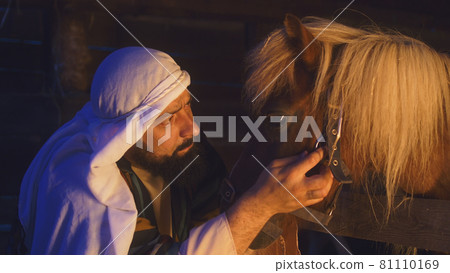 Joseph petting horse in dark barn 81110169