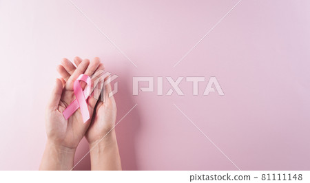 Hands holding pink ribbon, Breast cancer awareness, symbolic bow color raising awareness on women's breast tumor. Healthcare and medical concept. 81111148