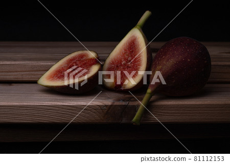 Photo of a fig cut in half and placed on a board, black background Photo of a fig cut in half and placed on a board, black background 81112153