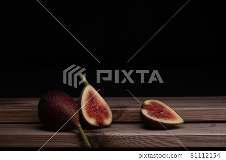 Photo of a fig cut in half and placed on a board, black background Photo of a fig cut in half and placed on a board, black background 81112154