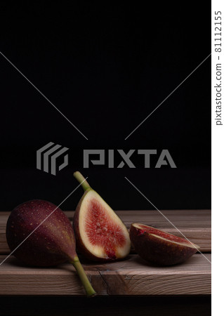 Photo of a fig cut in half and placed on a board, black background Photo of a fig cut in half and placed on a board, black background 81112155