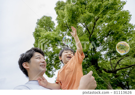 Boy and father playing with soap bubbles in the park Boy and father playing with soap bubbles in the park 81113626