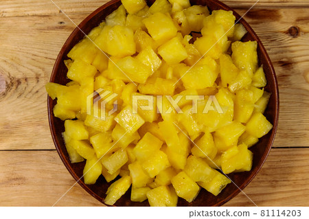 Diced pineapple in a plate on wooden table. Top view Diced pineapple in a plate on wooden table. Top view 81114203
