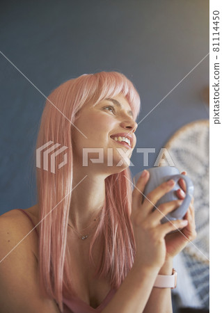 Attractive woman with colorful hair and mug of tasty beverage against blue wall with dreamcatcher Attractive woman with colorful hair and mug of tasty beverage against blue wall with dreamcatcher 81114450