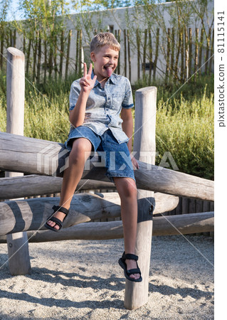 Cheerful and mischievous boy making faces while playing on playground. 81115141