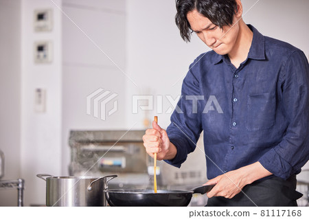 Image of a young man cooking in an apron cooking in the kitchen Image of a young man cooking in an apron cooking in the kitchen 81117168