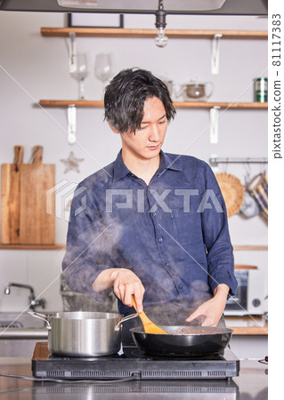 一個年輕人穿著圍裙在廚房做飯的形象 81117383