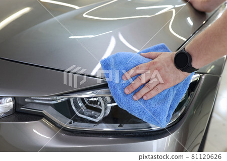 Man hand cleaning car and drying vehicle with microfiber cloth closeup 81120626