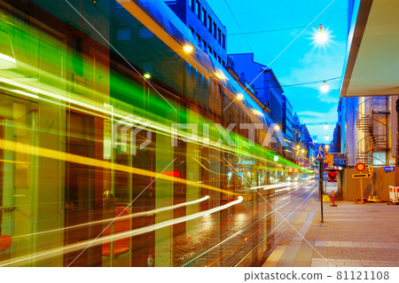 Helsinki, Finland. Tram Departs From A Stop On Street Aleksanterinkatu In Helsinki. Night View Of Aleksanterinkatu Street In Kluuvi District In Evening Or Night Illumination Helsinki, Finland. Tram Departs From A Stop On Street Aleksanterinkatu In Helsinki. Night View Of Aleksanterinkatu Street In Kluuvi District In Evening Or Night Illumination 81121108