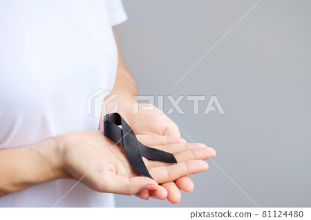 Woman holding black Ribbon for Melanoma and skin cancer, Vaccine injury awareness month, grief and rest in peace. Healthcare and Racist concept 81124480