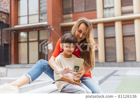 Two people, mother and little cute son strolling at street, trade square in summer time, outdoors. Family time, togehterness, parenting and happy childhood concept. Two people, mother and little cute son strolling at street, trade square in summer time, outdoors. Family time, togehterness, parenting and happy childhood concept. 81126136