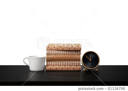 Alarm clock, stack of books and cup on tabletop against white background 81126798
