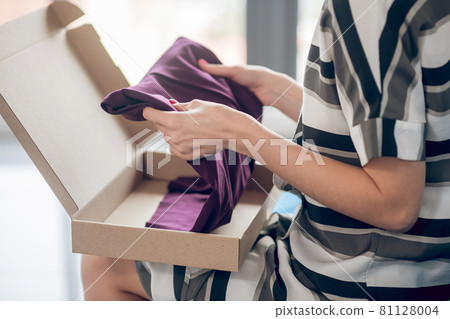 Experienced saleswoman preparing a garment for shipping 81128004