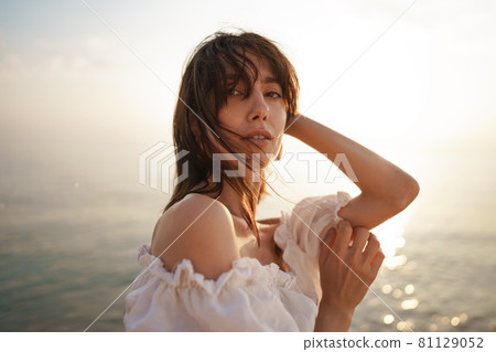 Portrait of young brunette haired woman at the beach at sunset 81129052