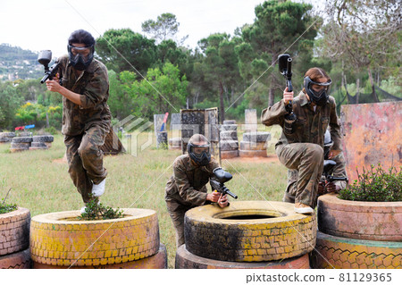 Two active opposing teams with guns playing paintball Two active opposing teams with guns playing paintball 81129365