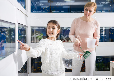 Girl with mother choosing aquarium fish 81129366