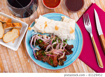 Grilled pork shashlik with onion, lavash and sauces 81129452