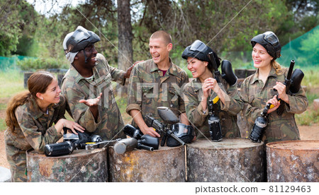 Smiling friends chatting after successful paintball match Smiling friends chatting after successful paintball match 81129463