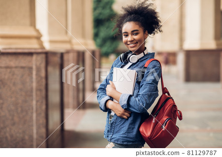 Cheerful Black Student Girl Hugging Books Posing Near College Building Cheerful Black Student Girl Hugging Books Posing Near College Building 81129787
