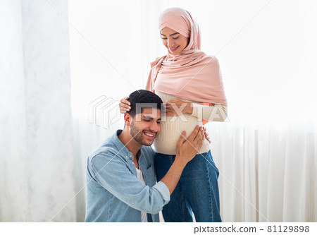 Happy arab man pressing his ear against his wife's pregnant belly, listening to his baby's heartbeat, free space Happy arab man pressing his ear against his wife's pregnant belly, listening to his baby's heartbeat, free space 81129898