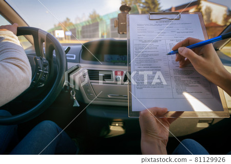 Examiner filling in driver's license road test form 81129926