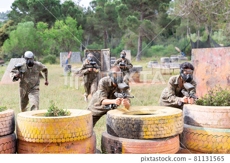 Two active opposing teams with guns playing paintball Two active opposing teams with guns playing paintball 81131565