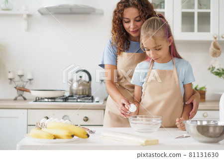 Mother and teen daughter making dough for pastry toghether in kitchen 81131630