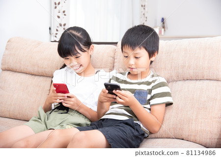 Men and women in elementary school looking at smartphones in the living room 81134986
