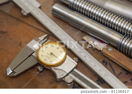 Close up scene of dial vernier caliper and the machine parts on the work bench. 81136917