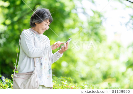 A senior woman who operates a smartphone, an old woman who touches a smartphone outdoors A senior woman who operates a smartphone, an old woman who touches a smartphone outdoors 81139990