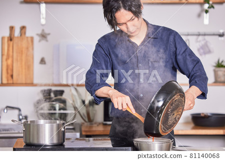 Image of a young man cooking in an apron cooking in the kitchen Image of a young man cooking in an apron cooking in the kitchen 81140068
