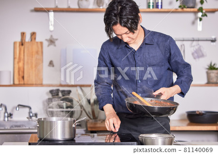 一個年輕人穿著圍裙在廚房做飯的形象 一個年輕人穿著圍裙在廚房做飯的形象 81140069