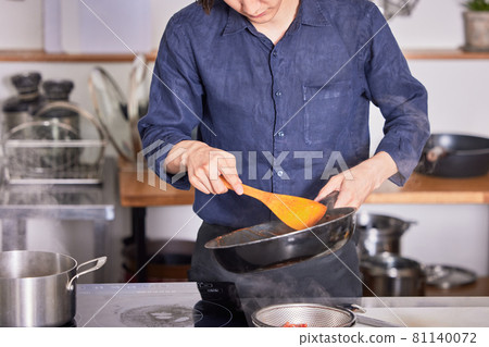 Hand cooking boy image of a young man wearing an apron cooking in the kitchen Hand cooking boy image of a young man wearing an apron cooking in the kitchen 81140072