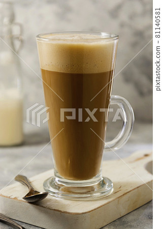 Coffee drink with whipped milk in tall glass cup with cinnamon. 81140581