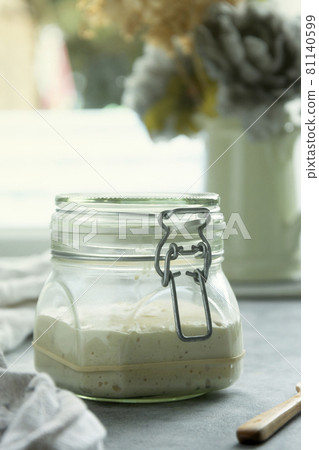 Sourdough starter in a jar, yeast-free leaven starter for healthy organic rustic bread, home baking concept Sourdough starter in a jar, yeast-free leaven starter for healthy organic rustic bread, home baking concept 81140599