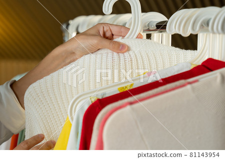 Close-up of a woman's hand choosing clothes and discounted T-shirts in a store, search or purchase 81143954