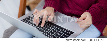 Closeup hand of young asian woman online shopping in Christmas with credit card on laptop computer. 81144158