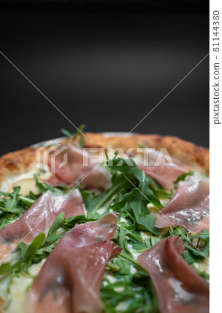 closeup of italian pizza with prosciutto, arugula and cheese on black background closeup of italian pizza with prosciutto, arugula and cheese on black background 81144380