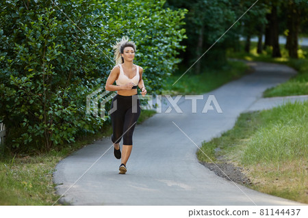 Active woman in sportswear runs in park. Active woman in sportswear runs in park. 81144437