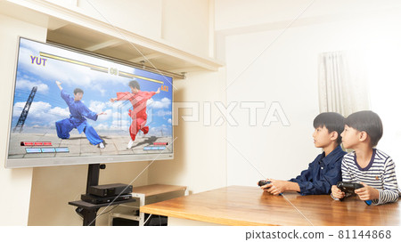 Two boys playing video games in the living room 81144868