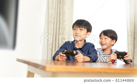 Two boys playing video games in the living room 81144869