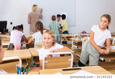 Positive primary school students are talking about homework at desk 81145101