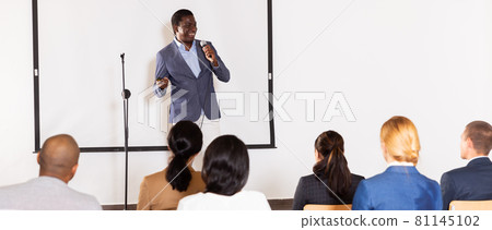 Male coach giving speech at conference hall 81145102