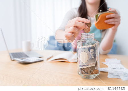 一個女人,她有一本家庭賬本,把硬幣放在一個小瓶子裡 一個女人,她有一本家庭賬本,把硬幣放在一個小瓶子裡 81146585
